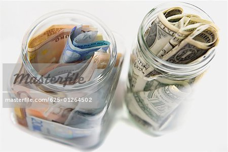 Euro and American bank notes squashed into two jars