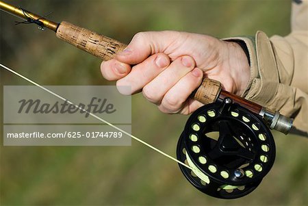 The hands of an adult man holding a sport fishing rod with reel