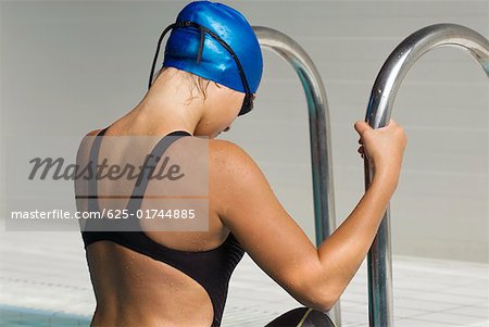 Side profile of a teenage girl stepping out from a swimming pool