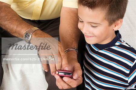 Mid section view of a senior man showing a mobile phone to his grandson