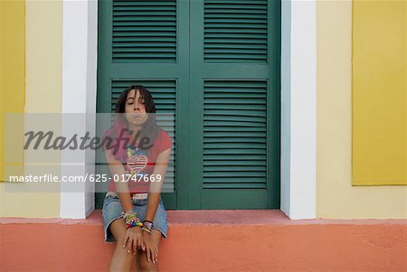 Young woman sitting on a window sill and making a face
