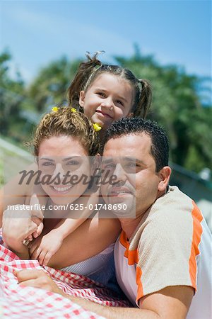 Portrait of a mid adult couple with their daughter lying on a picnic blanket