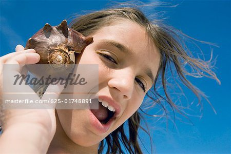 Portrait of a girl holding a conch shell to her ear