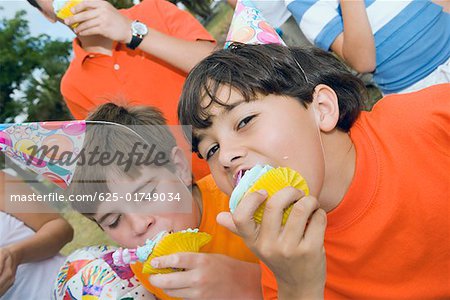 Portrait of two boys eating cupcakes