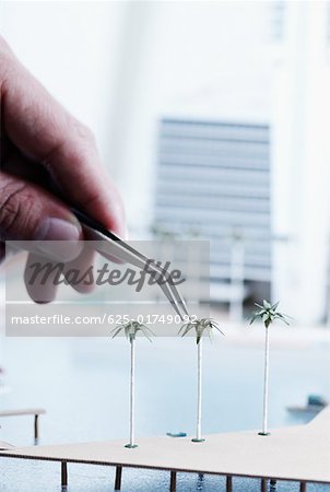 Close-up of a person's hand placing palm trees on an architectural model