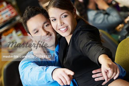 Close-up of a mid adult man with his arm around a teenage girl in a casino and pointing forward