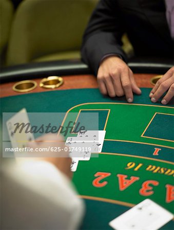 Close-up of a person's hand dealing with playing cards on a gambling table