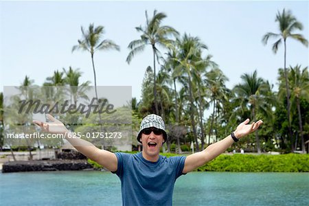 Young man standing with his arms outstretched and shouting, Captain Cook's Monument, Kealakekua Bay, Kona Coast, Big