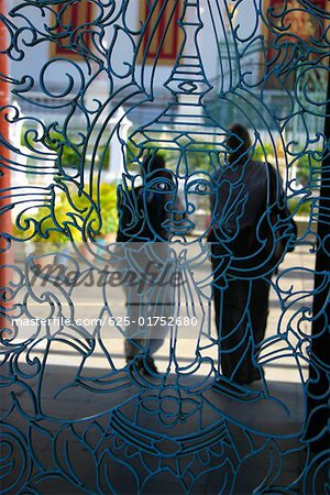 Two people standing behind the grill of a palace, Royal Palace, Phnom Penh, Cambodia