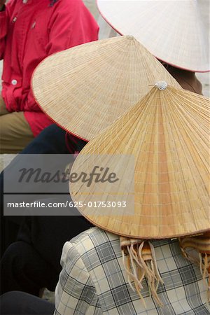 Close-up of three people wearing asian style conical hats, Hanoi, Vietnam