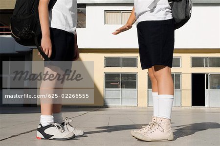 Low section view of two schoolboys standing in front of a school building