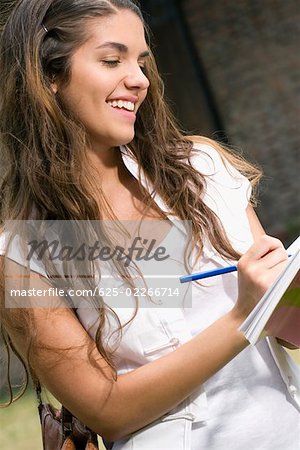 Close-up of a young woman writing and smiling