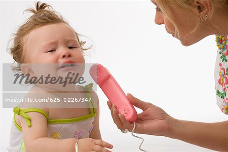 Close up of a mid adult woman giving the receiver of a toy phone to