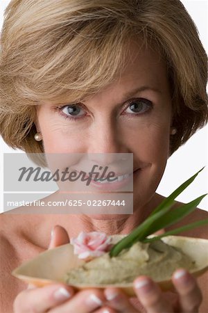 Portrait of a mature woman holding a bowl of herb