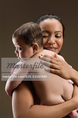 Close-up of a young woman carrying her son and smiling