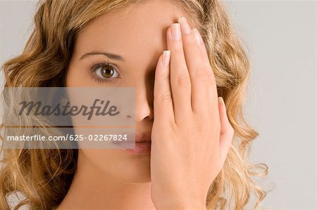 Portrait of a young woman covering her one eye