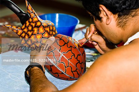 Rear view of a man painting on ceramics, Arrazola, Oaxaca State, Mexico