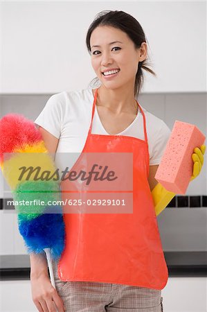 Portrait of a young woman holding a bath sponge and a feather duster