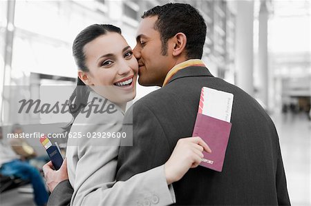 Close-up of a businessman kissing a businesswoman at an airport