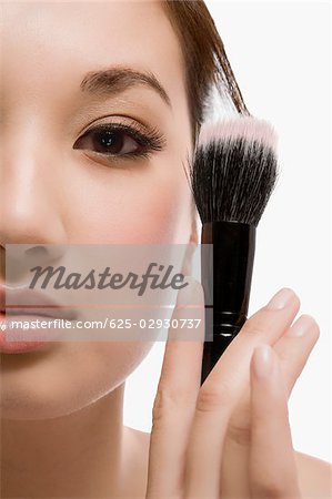 Close-up of a young woman holding a make-up brush