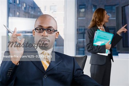 Portrait of a businessman thinking with a businesswoman standing in the background