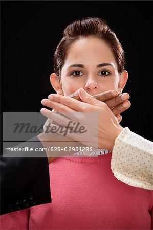 Close-up of a person's hand covering a businesswoman's mouth