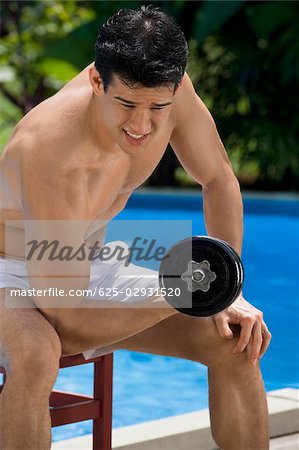 Close-up of a young man exercising with dumbbell