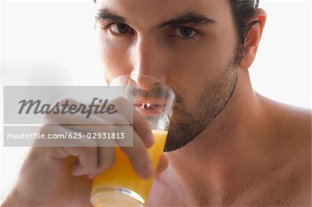 Close-up of a young man drinking a glass of juice