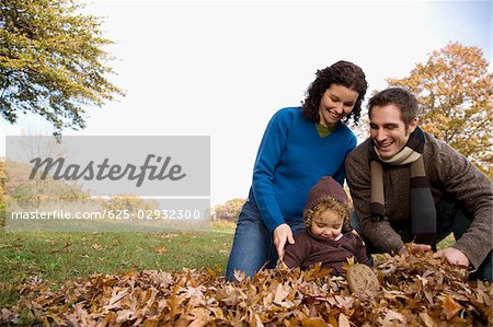 Couple and their daughter playing with leaves