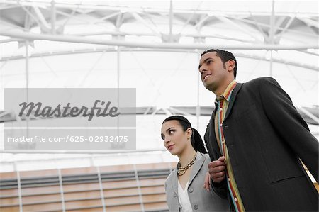Low angle view of a businessman and a businesswoman standing at an airport