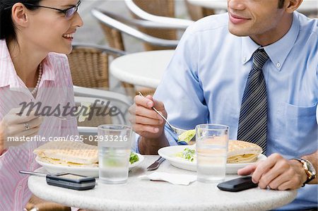 Businessman and a businesswoman having lunch at a sidewalk cafe