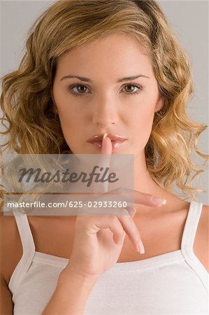 Portrait of a young woman with finger on lips