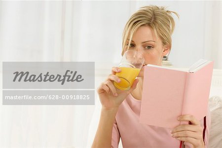 Woman reading a book, drinking juice