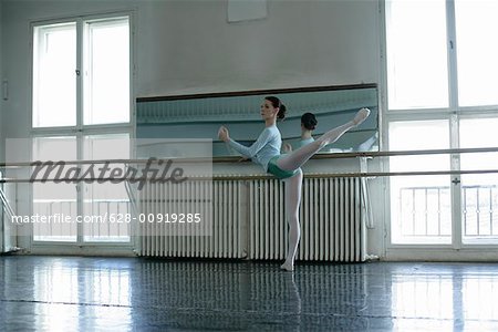 A female ballet dancer exercising a attitude at ballet bare