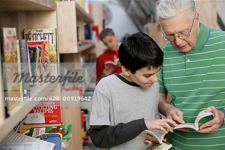 Grandfather and boy reading a book in front of a bookshelf, fully_released