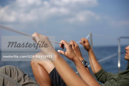 Couple holding on a safety line on a sailboat