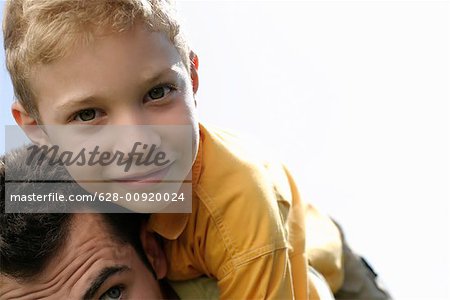 Father giving son a piggyback ride, boy looking at camera