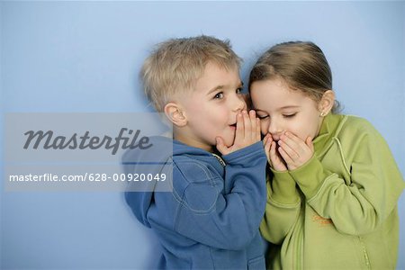 Little boy whispering in girl's ear