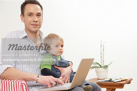 Father with son and laptop at lap looking at camera