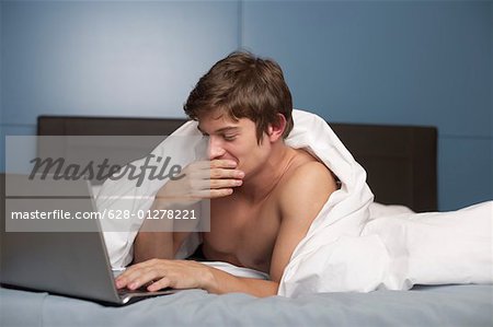 Young naked man in bed, close-up, portrait