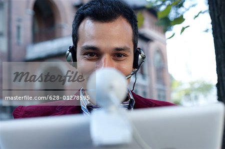 Man with headset using a laptop with webcam
