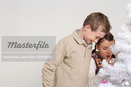 Girl and boy next to a white Christmas tree