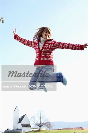 Young woman jumping into the air in front of a small town