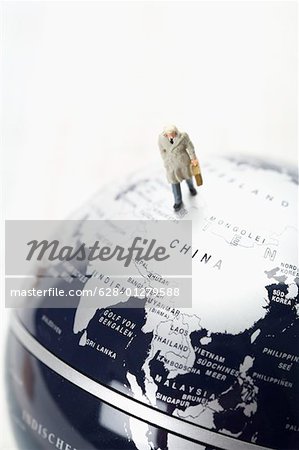 Businessman figurine with briefcase walking on globe