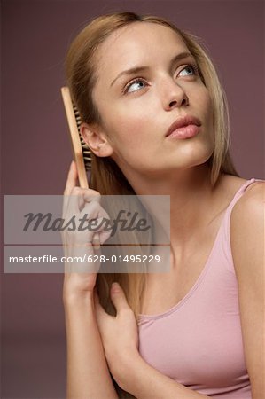 Young blonde woman brushing her hair, close-up