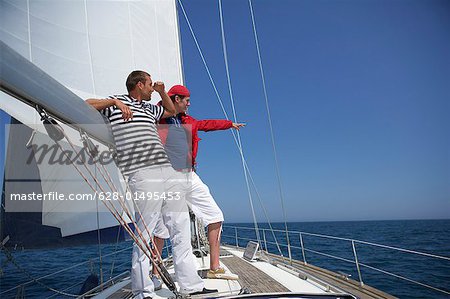 Two men in blue shirts sitting on sailing yacht in the port Stock
