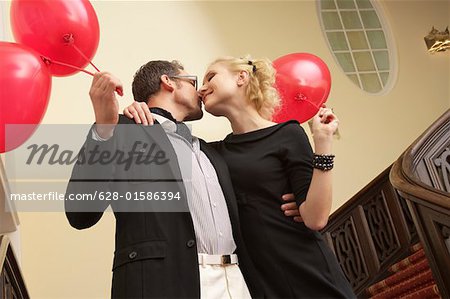 Couple with balloons embracing each other on a staircase