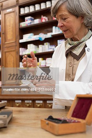 Female pharmacist using old fashioned scale to preparing drugs