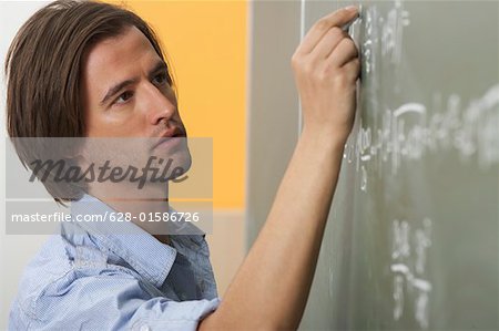 Man is writing prims on a board