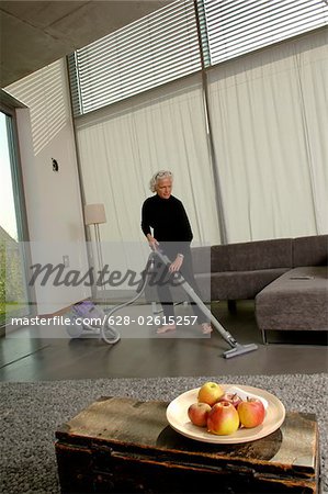 Senior woman vacuuming living room
